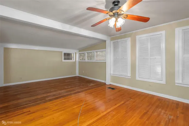 a view of an empty room with window and chandelier fan