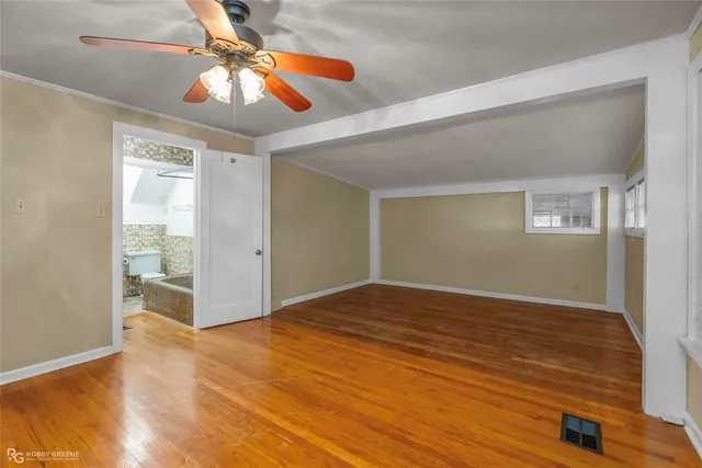 a view of an empty room with window and wooden floor