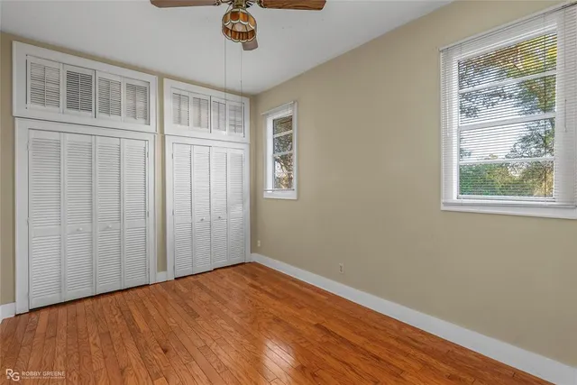 a view of empty room with wooden floor and fan
