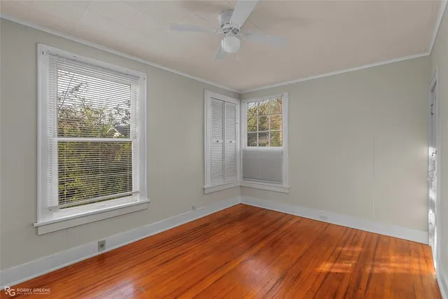 a view of empty room with wooden floor and fan