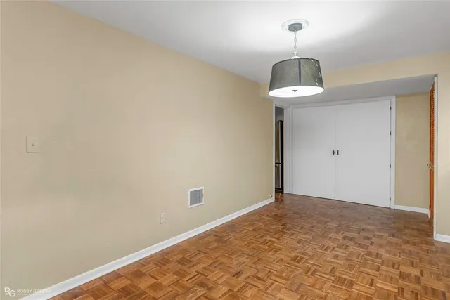 a view of an empty room with wooden floor and chandelier