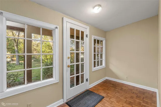 a view of an empty room with wooden floor and windows