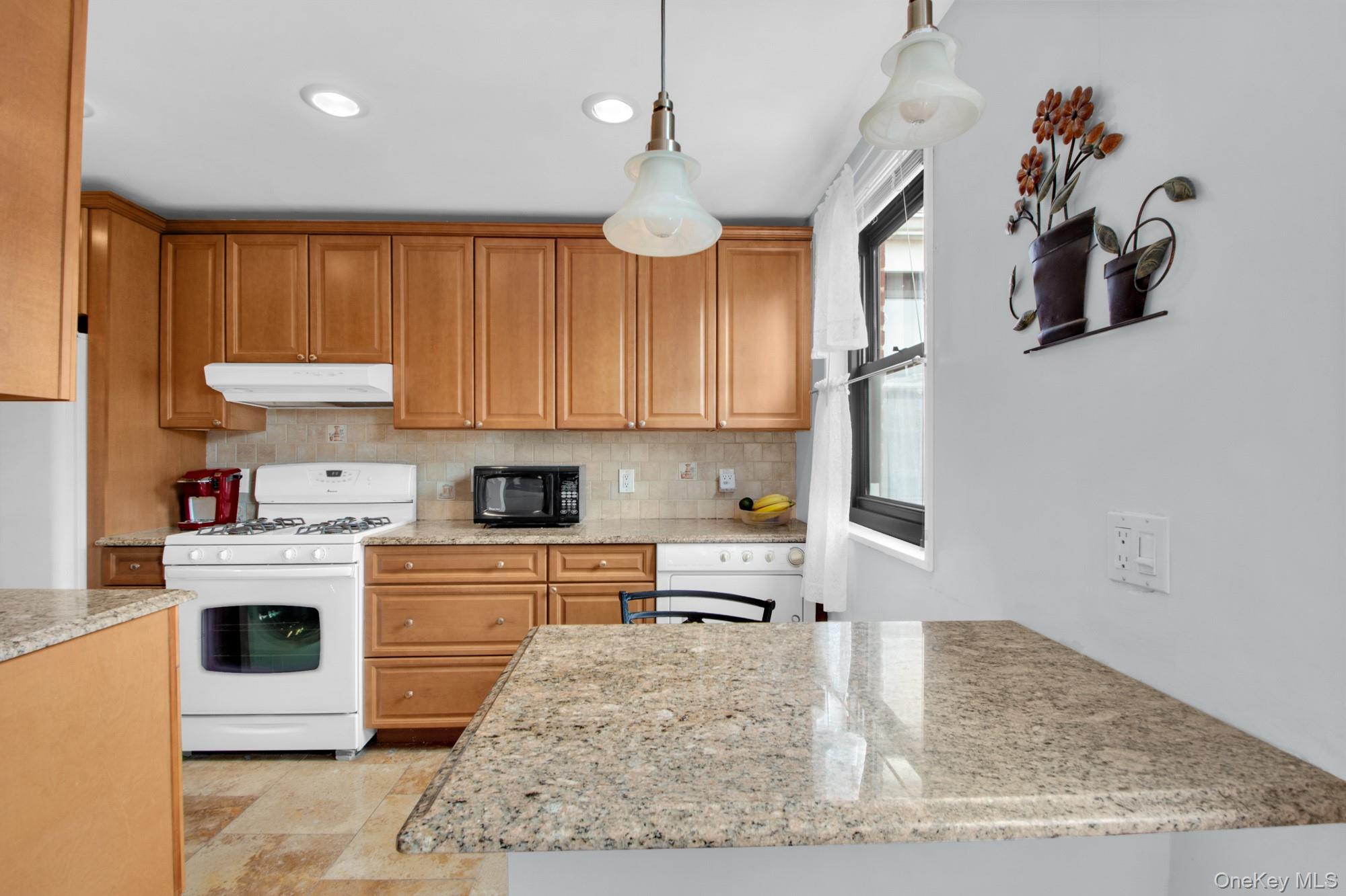 21-29 Utopia Parkway, Unit UPSTAIRS Queens, NY 11357 - Photo 3 of 8 a kitchen with kitchen island granite countertop a sink cabinets and window