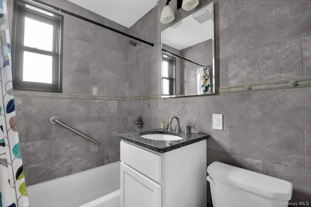a bathroom with a granite countertop sink a toilet and bathtub