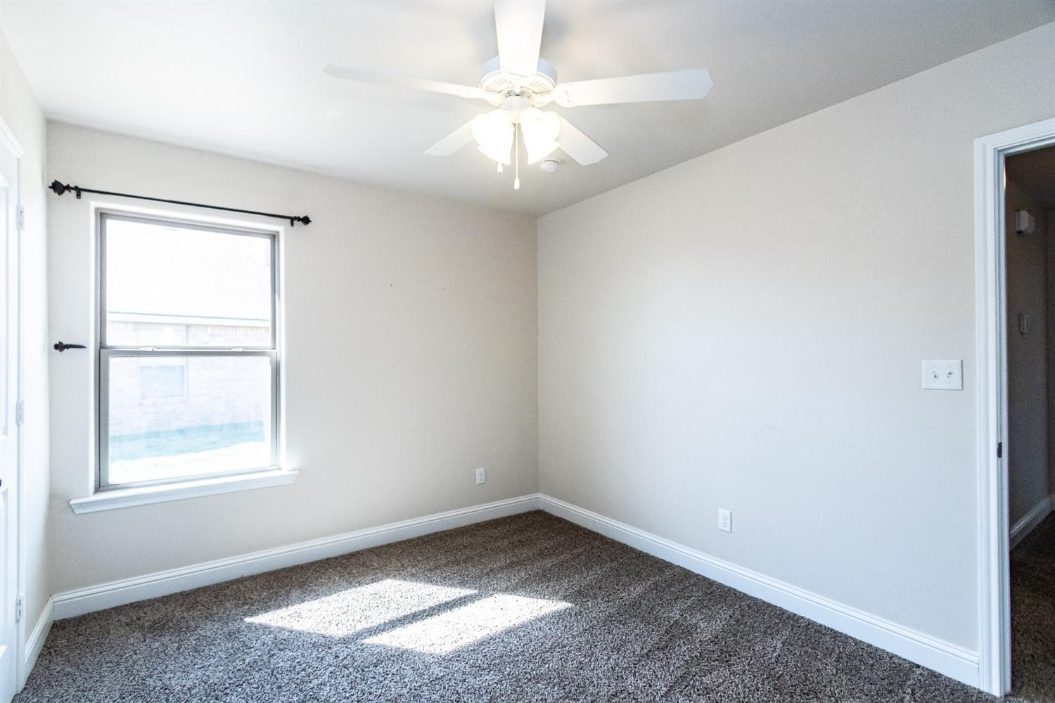9706 Ridgely Avenue Lubbock, TX 79424 - Photo 13 of 32 an empty room with windows and fan