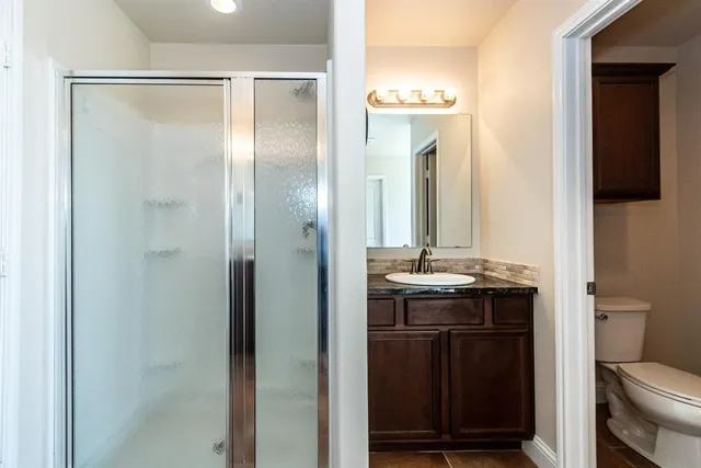 a bathroom with a granite countertop sink a toilet a mirror and vanity