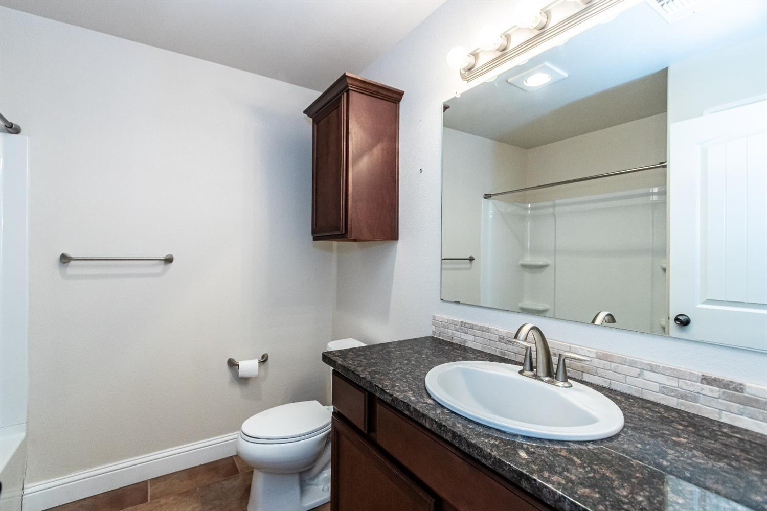 9706 Ridgely Avenue Lubbock, TX 79424 - Photo 26 of 32 a bathroom with a granite countertop sink toilet and mirror