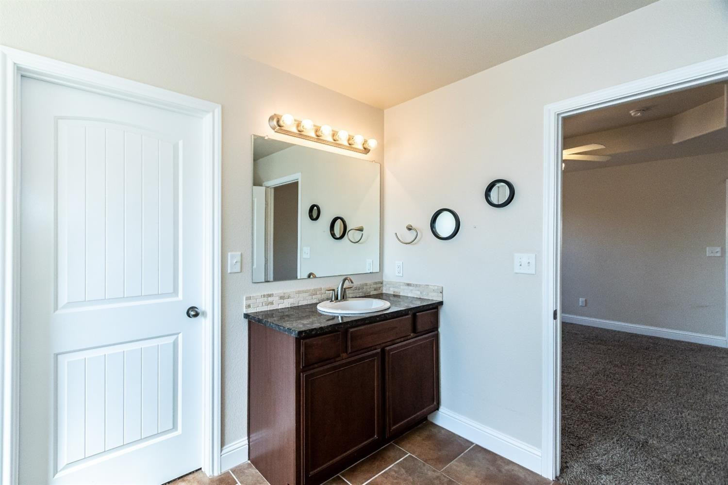9706 Ridgely Avenue Lubbock, TX 79424 - Photo 29 of 34 a bathroom with a granite countertop sink a mirror and a shower