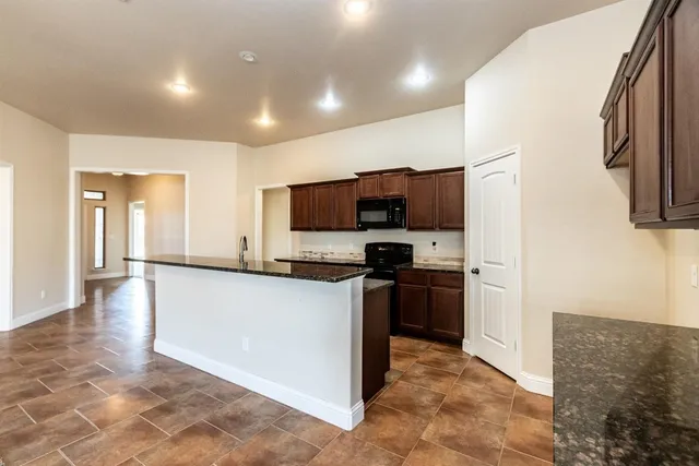 a kitchen with stainless steel appliances granite countertop a refrigerator a stove top oven a sink and dishwasher