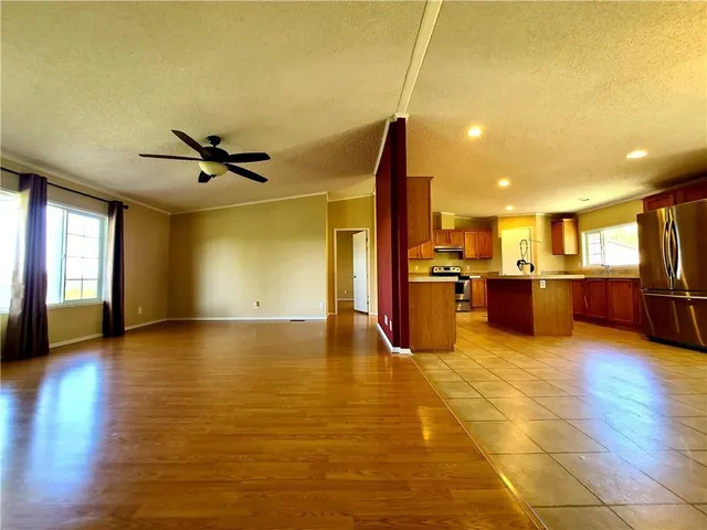a view of an empty room with kitchen view and a window