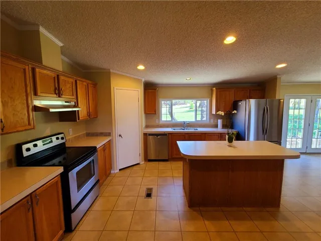 a kitchen with kitchen island granite countertop a sink counter top space appliances and a window