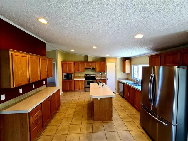 a large kitchen with stainless steel appliances kitchen island granite countertop a large counter top furnished and stainless steel appliances