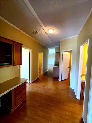 a view of an empty room with wooden floor and windows
