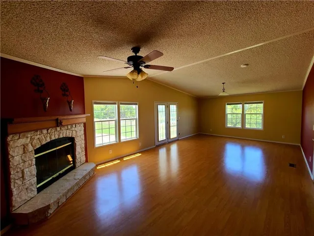 a view of an empty room with wooden floor fireplace and a window