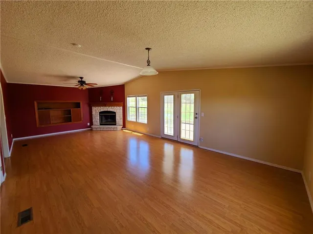 a view of an empty room with window and wooden floor