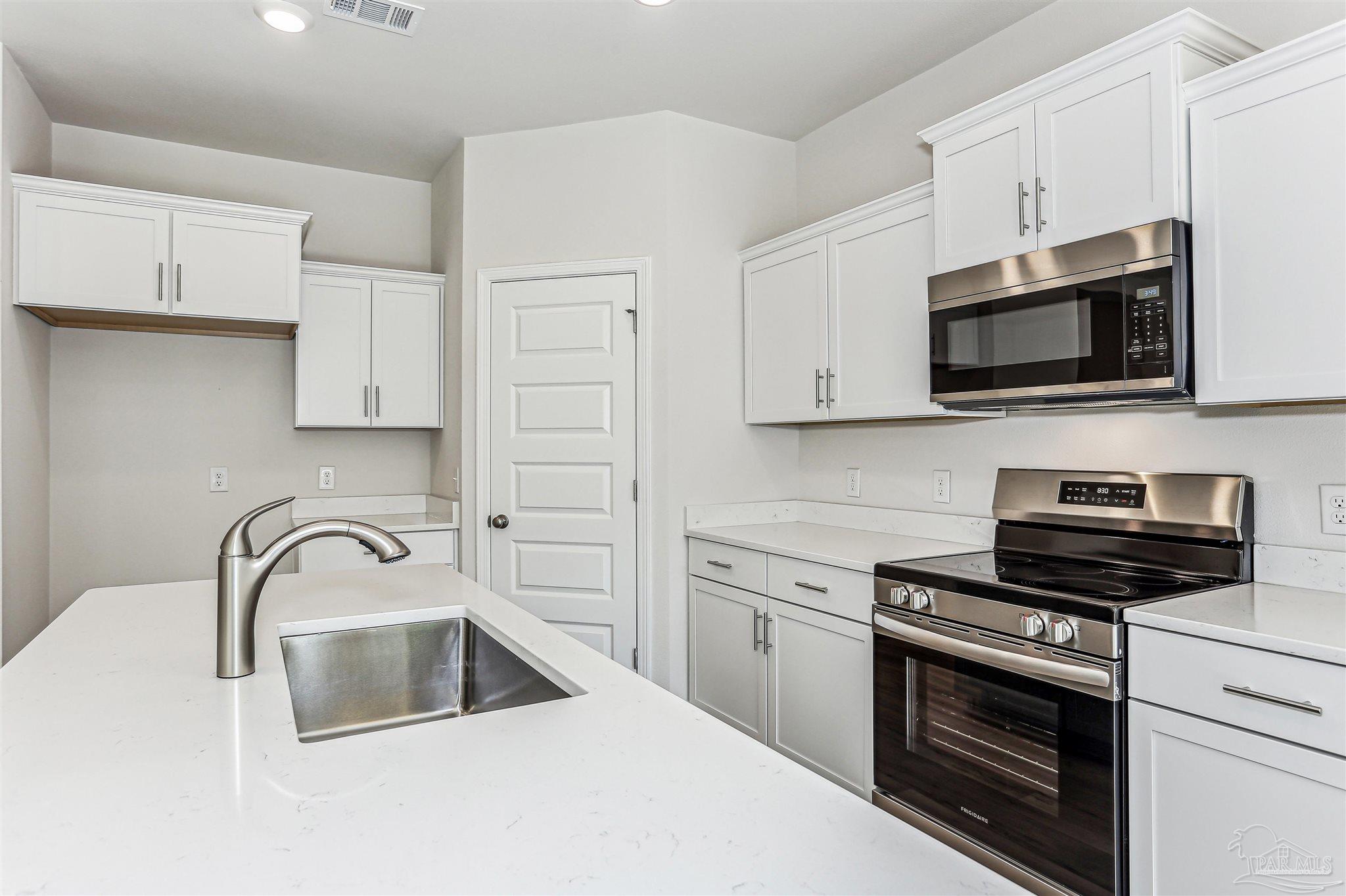 1644 Slate Drive Cantonment, FL 32533 - Photo 5 of 28 a kitchen with white cabinets a sink and stainless steel appliances
