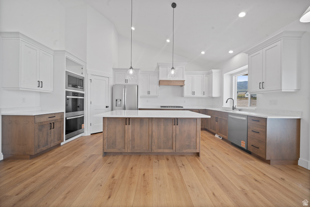 1117 East Shilow Road, Unit 106 Erda, UT 84074 - Photo 4 of 21 Modern kitchen featuring a large central island, light wood-finish flooring, and vaulted ceilings