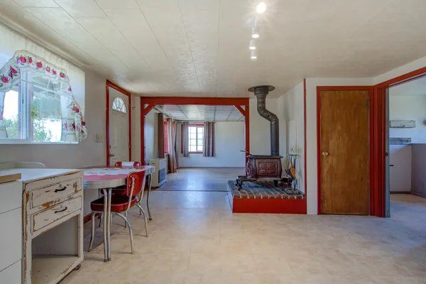 an empty room with wooden floor and windows with curtains