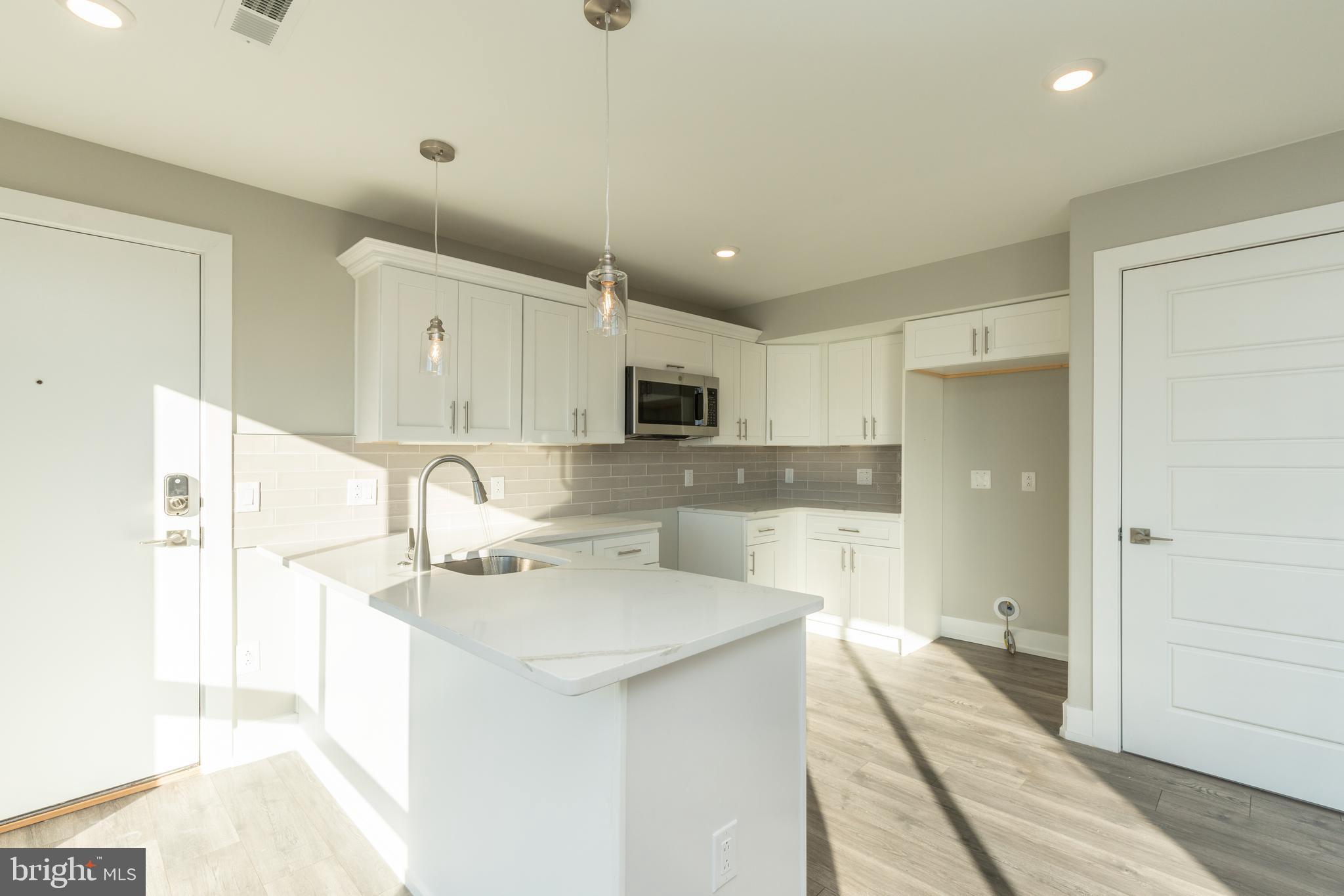 2517 Hope Street, Unit 5 Philadelphia, PA 19133 - Photo 3 of 35 a large white kitchen with a sink and dishwasher a refrigerator with wooden floor