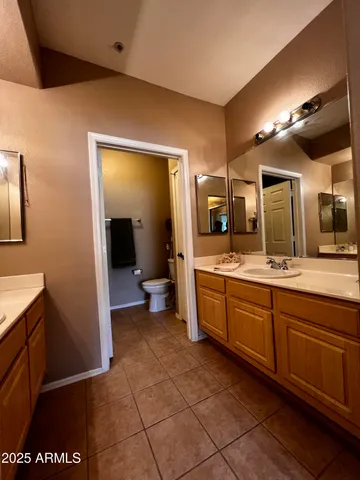 a large bathroom with a large mirror vanity and toilet
