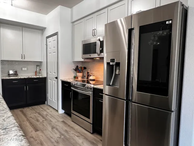 a kitchen with stainless steel appliances granite countertop a refrigerator a stove a sink and a microwave