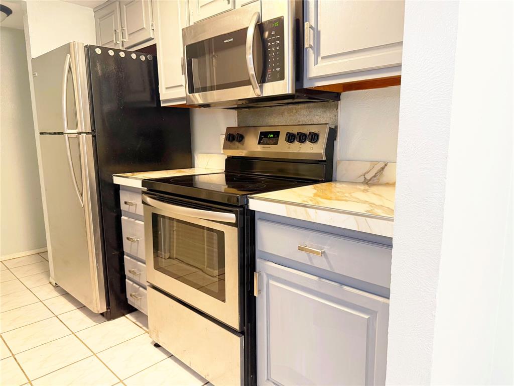 11311 Audelia Road, Unit 161 Dallas, TX 75243 - Photo 6 of 15 Kitchen featuring stainless steel appliances, light countertops, light tile patterned floors, and white cabinetry