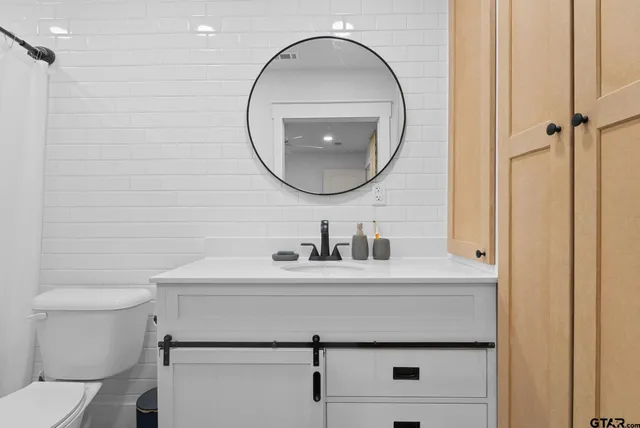 a bathroom with a sink mirror vanity and toilet