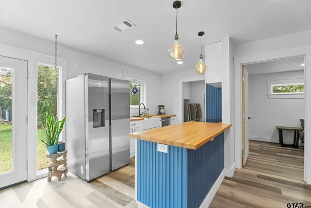 a room with stainless steel appliances kitchen island granite countertop wooden floor and a window