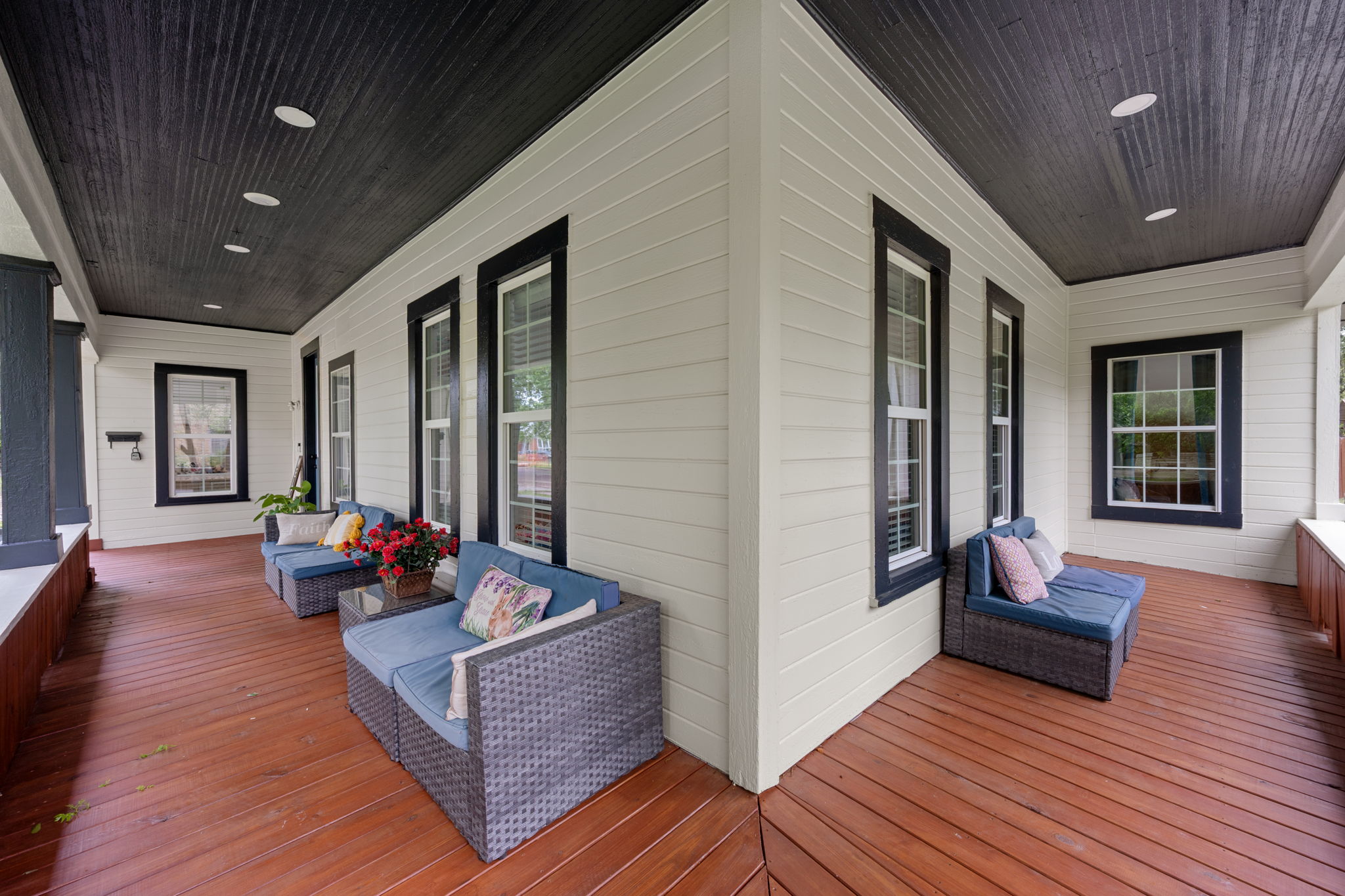 602 East 6th Street Cameron, TX 76520 - Photo 4 of 40 Spacious covered porch with rich wood plank flooring, a dark paneled ceiling featuring recessed lighting, and crisp white siding with contrasting dark trim around multiple windows