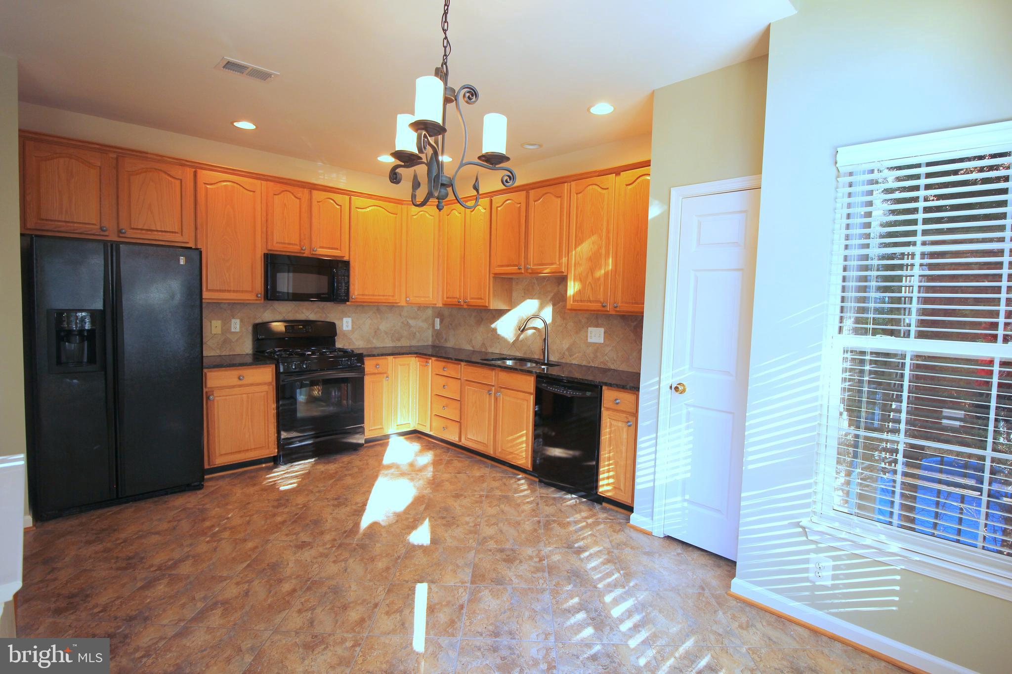 43605 Ryder Cup Square Ashburn, VA 20147 - Photo 11 of 48 a kitchen with stainless steel appliances kitchen island granite countertop a refrigerator a stove and a sink with wooden floor