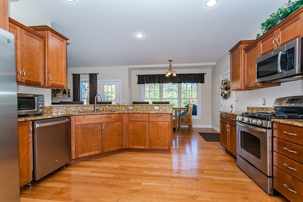 30 April's Way Tewksbury, MA 01876 - Photo 6 of 42 a kitchen with stainless steel appliances granite countertop a stove top oven a sink dishwasher a dining table and chairs with wooden floor