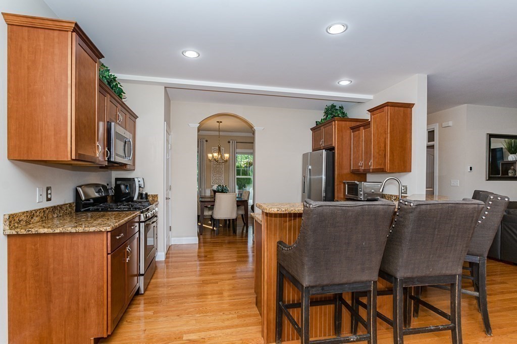 30 April's Way Tewksbury, MA 01876 - Photo 8 of 42 a kitchen with stainless steel appliances granite countertop a stove a sink dishwasher a microwave oven and a dining table with wooden cabinet