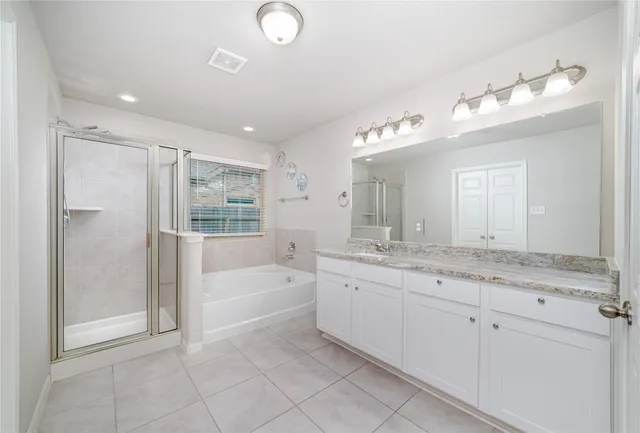 a spacious bathroom with a granite countertop sink a mirror and a bathtub