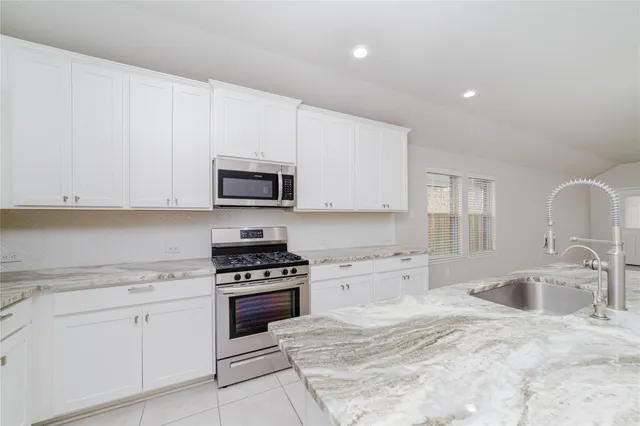 a kitchen with granite countertop white cabinets and stainless steel appliances