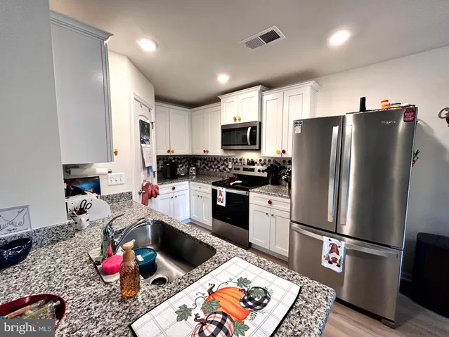 a kitchen with stainless steel appliances kitchen island granite countertop a refrigerator stove top oven and sink