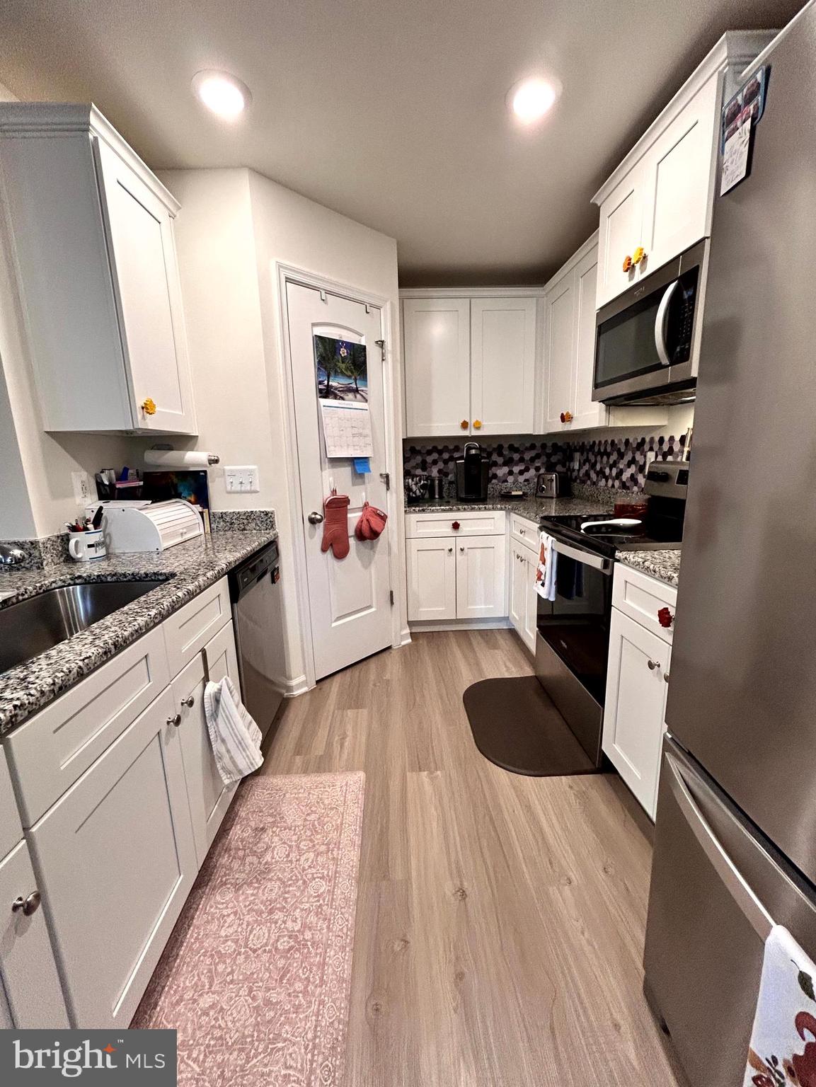 90 Rappahannock Run Falling Waters, WV 25419 - Photo 9 of 47 a kitchen with stainless steel appliances kitchen island granite countertop a refrigerator a sink dishwasher a stove and white cabinets with wooden floor