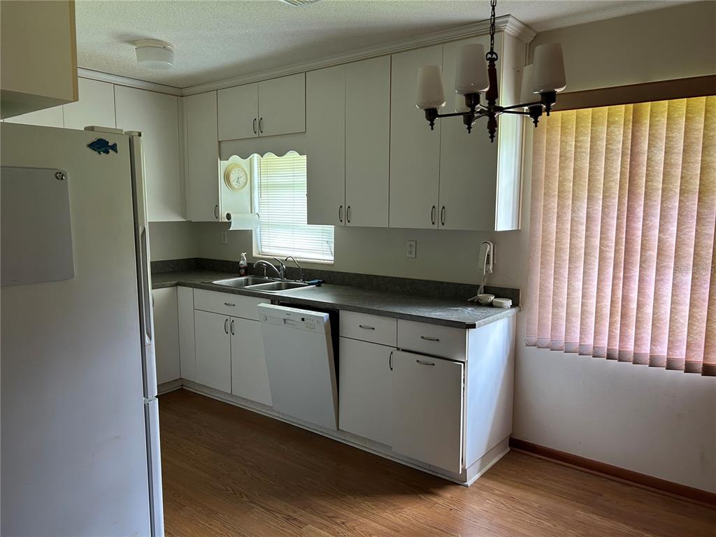 24121 Armadillo Road Astor, FL 32102 - Photo 5 of 11 a kitchen with granite countertop white cabinets and white appliances