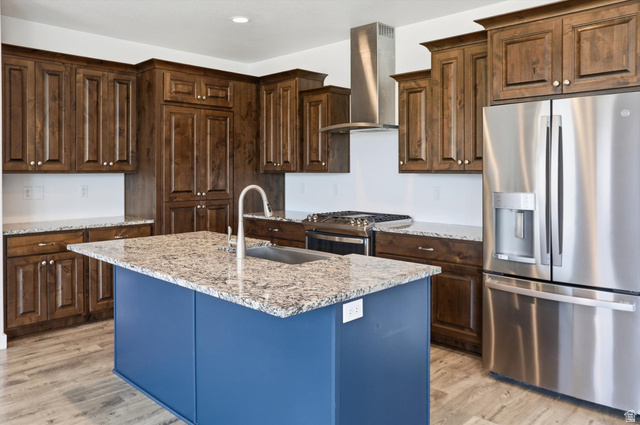 3636 West 910 South Syracuse, UT 84075 - Photo 31 of 70 Kitchen featuring wood cabinetry, stainless steel appliances, a center island with a sink, granite countertops, and wood-finish flooring