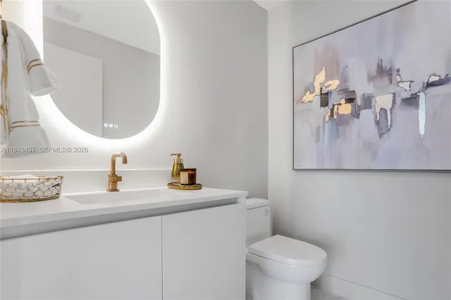 a view of a hallway with wooden floor and a bathroom