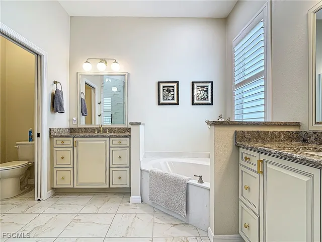 a bathroom with a granite countertop sink a toilet mirror and bathtub