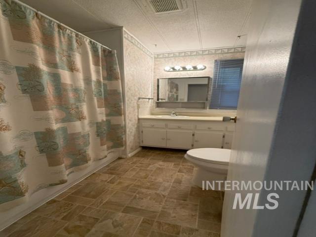 1360 Pioneer Road Weiser, ID 83672 - Photo 14 of 47 Bathroom featuring a white vanity with integrated sink, wall-mounted mirror, and brown-toned tile flooring