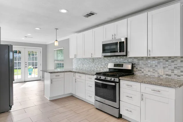 a kitchen with granite countertop white cabinets stainless steel appliances and a window