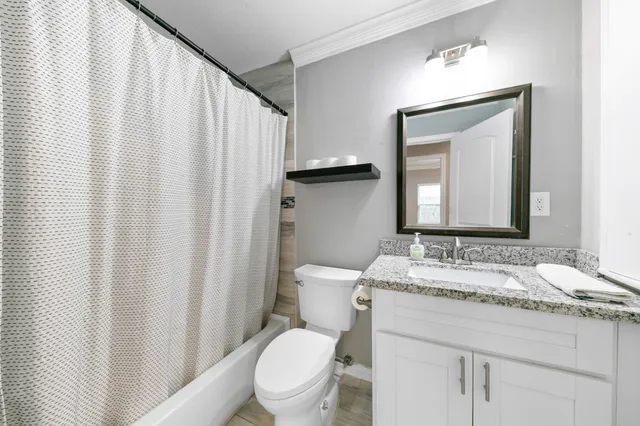 a bathroom with a granite countertop sink toilet and mirror