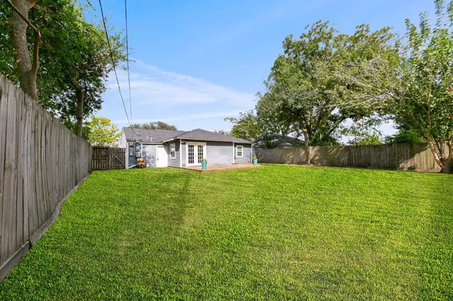 a view of a house with a yard and a large tree
