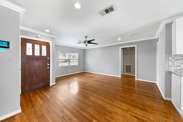 a view of an empty room with window and wooden floor