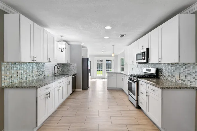 a large kitchen with stainless steel appliances granite countertop a stove a sink dishwasher and a refrigerator