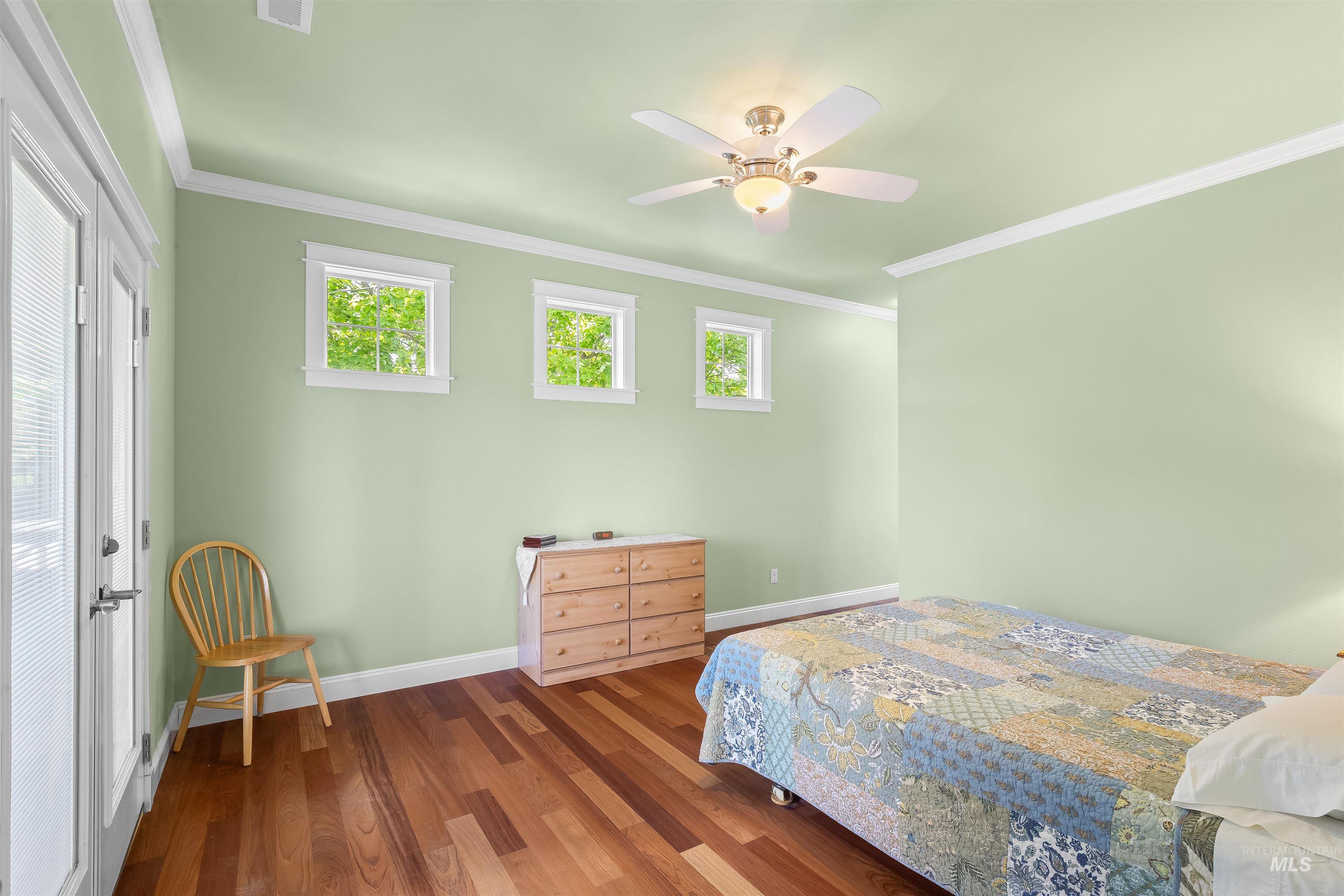 1617 Pine Cone Road Moscow, ID 83843 - Photo 20 of 44 Spacious room featuring wood-finish flooring, light green walls, white crown molding, and a ceiling fan with integrated lighting