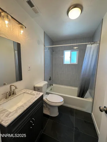 a bathroom with a granite countertop sink a toilet a mirror and bathtub
