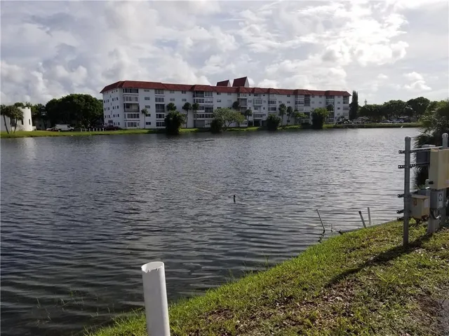 a view of a lake next to a building with large trees
