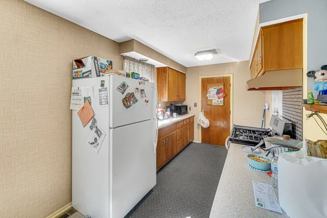 a kitchen with stainless steel appliances a refrigerator a sink a stove a chimney a refrigerator and cabinets